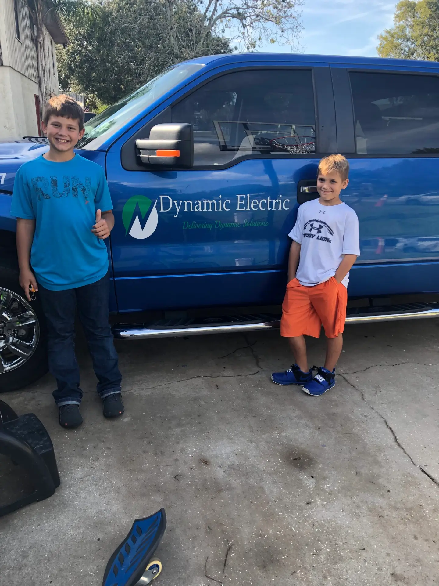 Two boys standing next to a van with a Dynamic Electric logo.