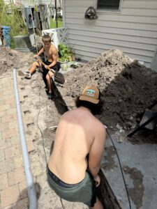 Two people working on a backyard project involving soil and pavers.