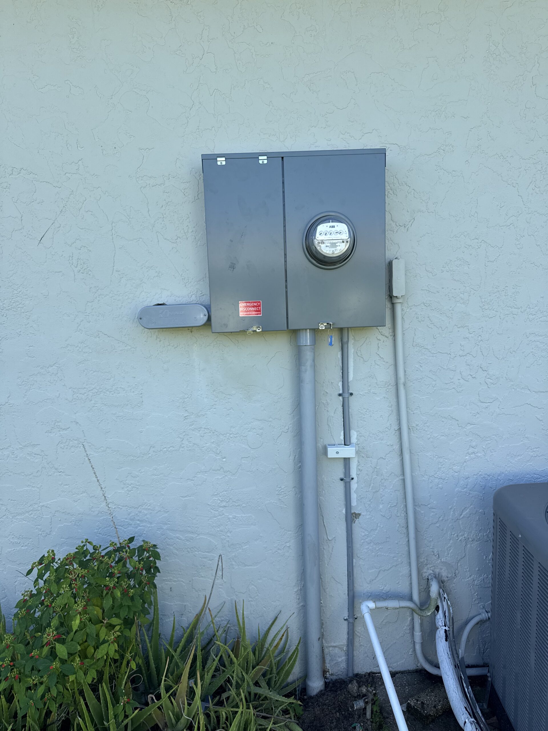Electrical service meter and panel mounted on an exterior wall.