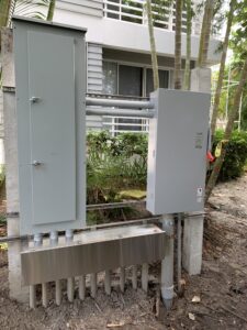 Two electrical panels mounted outside near a garden path.