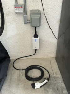 Electric vehicle charging cable neatly coiled beside a mounted charger.