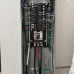 Open electrical panel showing circuit breakers and wiring.