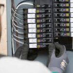 Technician inspecting circuit breakers in electrical panel.