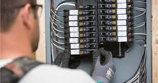 Technician inspecting circuit breakers in electrical panel.
